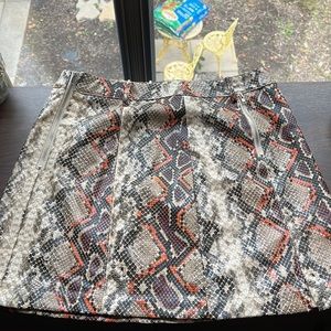 A snake skin skirt with decorative zippers, buttons, and belt loops